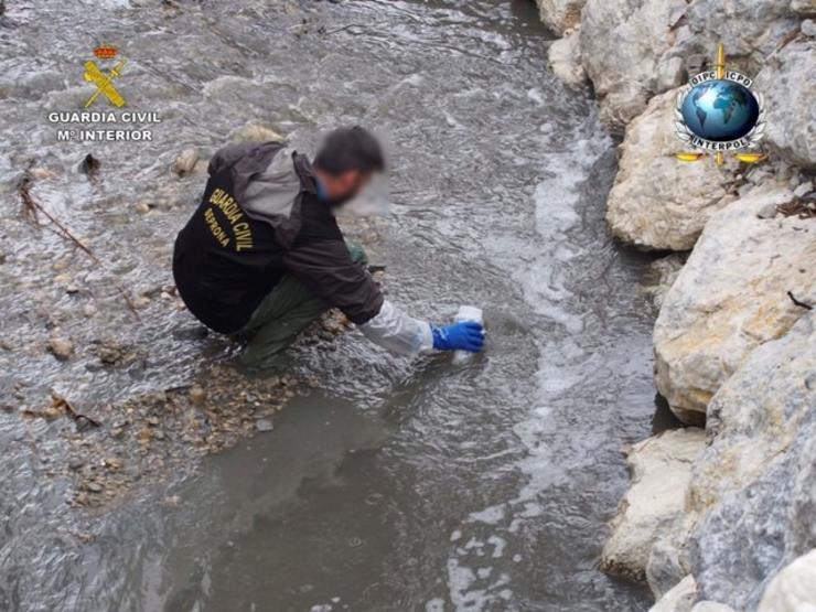 Un axente toma mostras de auga contaminada  GARDA CIVIL 