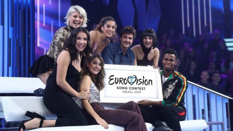 Sabela, con outros concursantes e un cartel de Eurovisión 2019. AXM