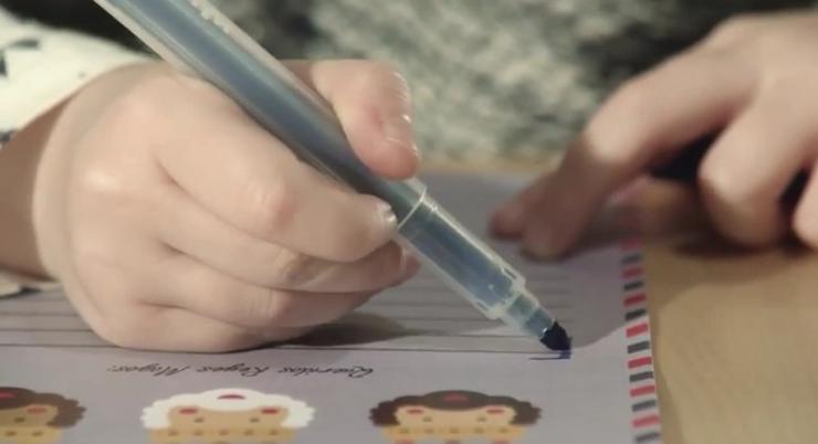 Un neno con diversidade funcional escribindo unha carta aos Reis 