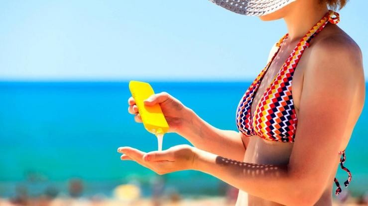 Unha muller bota unha crema de protección do sol nunha praia durante o verán / López-Doriga Digital