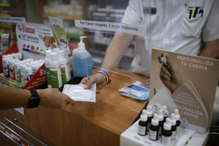 Un farmacéutico entrega a un cliente una das máscaras KN95 que recibiu na súa farmacia. Óscar Canas - Europa Press 