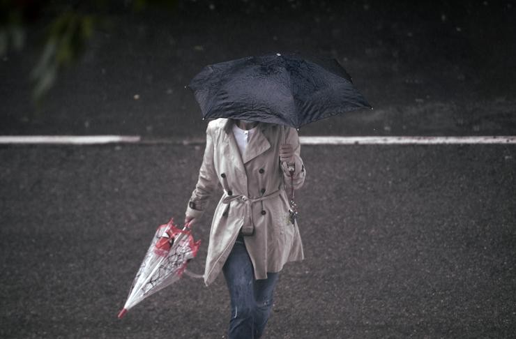 Unha persoa camiña baixo a choiva protexida cun paraugas / Europa Press