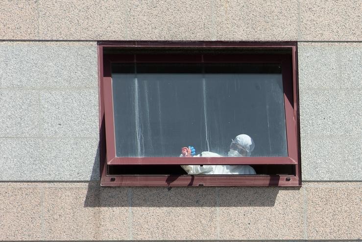 Un traballador protexido é visto por un dos cristais da residencia de maiores DomusVi de Outeiro de Rei en Lugo.. Carlos Castro - Europa Press - Arquivo / Europa Press