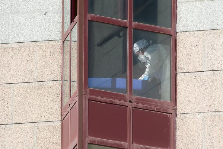 Un traballador protexido é visto por un dos cristais dunha residencia de maiores DomusVi. Carlos Castro - Europa Press