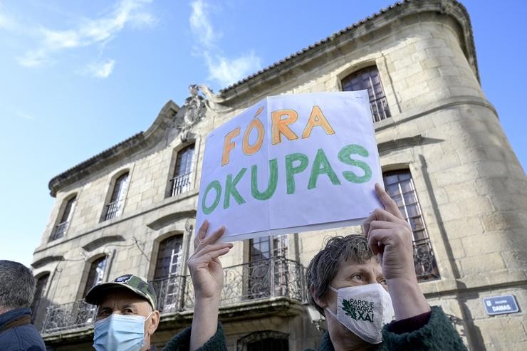 Unha persoa sostén un cartel onde se pode ler "Fóra okupas" durante unha marcha cívica para pedir a devolución da Casa Cornide / M. Dylan - Europa Press.