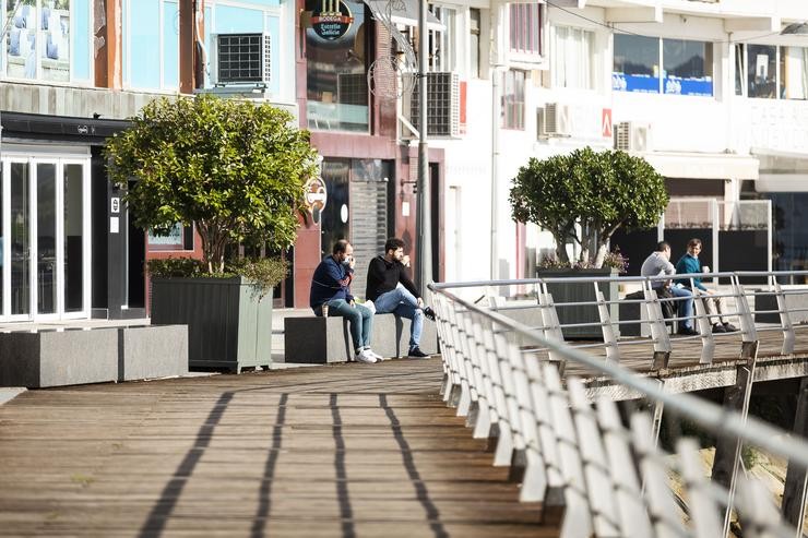 Dúas persoas permanecen sentadas nun banco de Sanxenxo, último municipio galego en decretarse o máximo grao de restricións. Beatriz Ciscar - Europa Press 