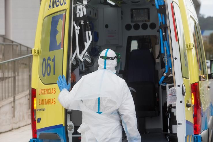 Un traballador sanitario totalmente protexido pecha a porta dunha ambulancia tras recoller a un ancián da residencia de anciáns  