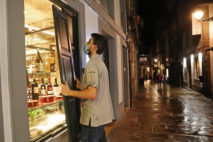 Un camareiro protexe o seu establecemento á hora do peche polas medidas ordenadas pola crise do Covid-19, en Santiago de Compostela, Galicia, (España), a 6 de novembro.. Álvaro Ballesteros - Europa Press 