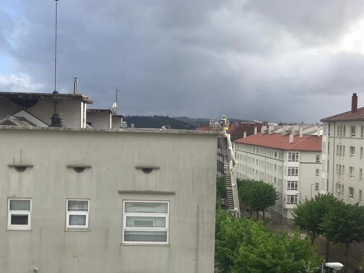 Bombeiro no tellado dun edificio do barrio de Fontiñas, en Santiago, tras a caída dun tellado polo temporal 