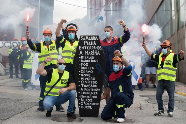 Traballadores de Alcoa pousan xunto a un féretro de cartón durante unha nova manifestación tras o anuncio realizado pola empresa do despedimento colectivo de ata 534 traballadores dos 610 das súa planta en San Cibrao 