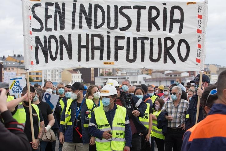 Traballadores de Alcoa camiñan pola rúa cunha pancarta na que se le 
