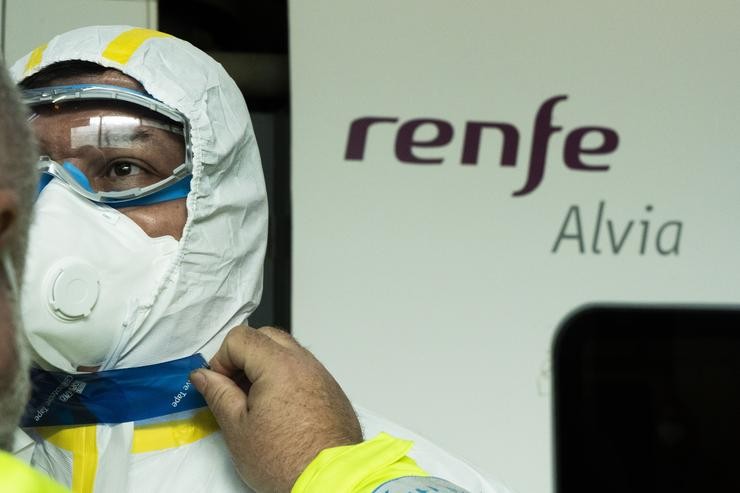 Un traballador sanitario termina de colocarse o seu traxe de protección xunto a un tren Alvia durante o simulacro realizado polo Ministerio de Sanidade na estación de Atocha de Madrid 