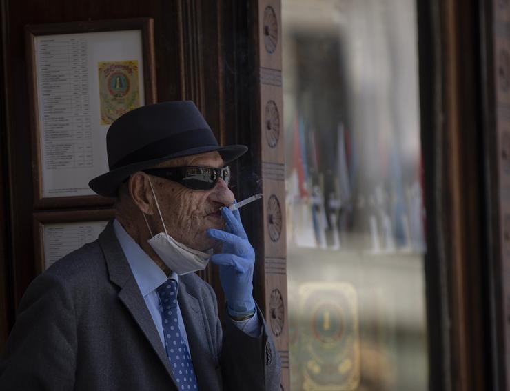 Un home con máscara e luvas fumando un cigarro durante o quinto día da fase 2 en Sevilla (Andalucía, España), a 29 de maio de 2020.. María José López - Europa Press - Arquivo 