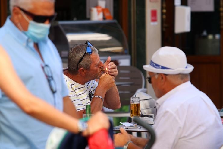 Persoas fumando en terrazas e vías públicas  durante o día no que se decretou a prohibición de fumar en espazos públicos se non se respecta a distancia de seguridade establecida. Málaga a 14 de agosto do 2020. Álex Zea - Europa Press 