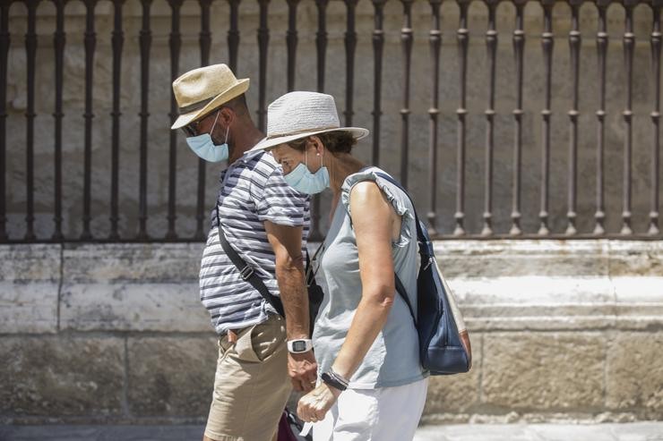 Dúas persoas camiñan con máscara e chapeu durante unha onda de calor africana.. María José López - Europa Press