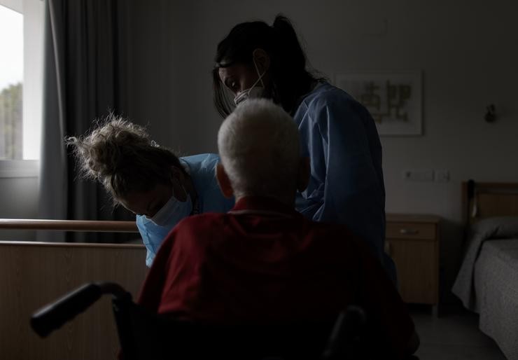 Estefanía (d), técnico sociosanitario e Virtu (i), enfermeira, ambas as traballadoras do Centro de Maiores Casabranca Villaverde (Av. de Rafaela Ybarra, 135), asisten a un residente / Eduardo Parra - Arquivo