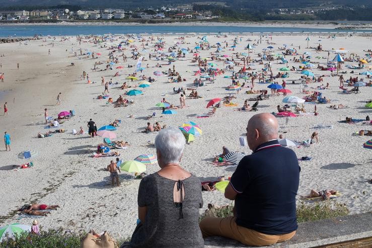 Dúas persoas observan a praia na Mariña 