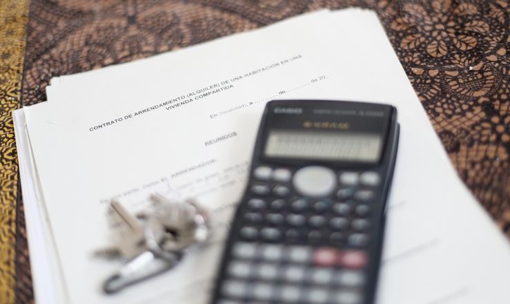 Unha calculadora e unhas chaves sobre un contrato de arrendamento (aluguer) dunha habitación nunha vivenda compartida 