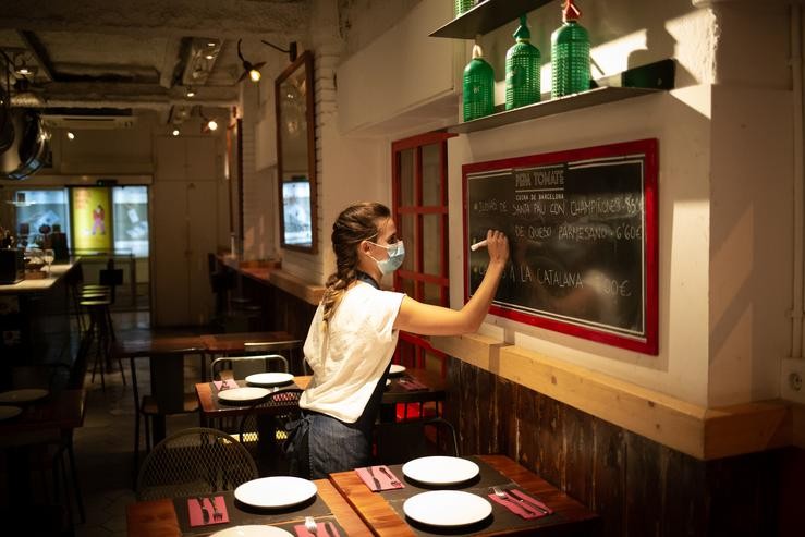 Arquivo - Unha camareira apunta pratos nunha lousa no interior dun bar. David Zorrakino - Europa Press - Arquivo