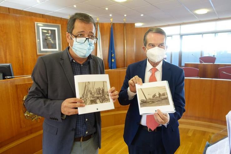 O xornalista Eduardo Rolland e o alcalde de Vigo, Abel Caballero, mostran dúas fotografías dunha expedición de arqueoloxía submarina realizada en 1870 na ría, as máis antigas imaxes fotográficas da baía viguesa.. CONCELLO DE VIGO / Europa Press