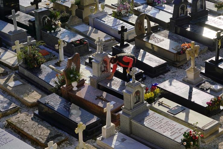 Unha muller limpa unha lápida do cemiterio de Quintana dos Mortos de Santa María A Nova, a 26 outubro de 2021, en Noia / Álvaro Ballesteros - Arquivo