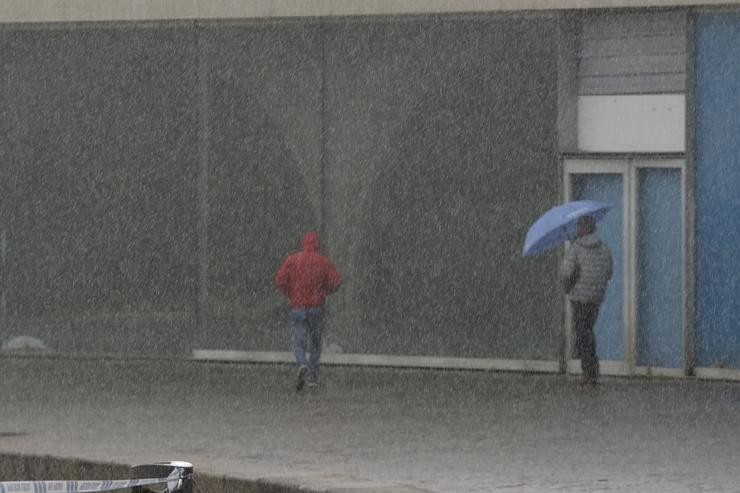 Dúas persoas camiñan polo paseo marítimo mentres chove, a 8 de decembro de 2021, na Coruña, Galicia, (España). A borrasca Varra fixo que a Xunta haxa activado para todo o litoral galego unha alerta laranxa por temporal costeiro. Segundo as pre. M. Dylan - Europa Press / Europa Press
