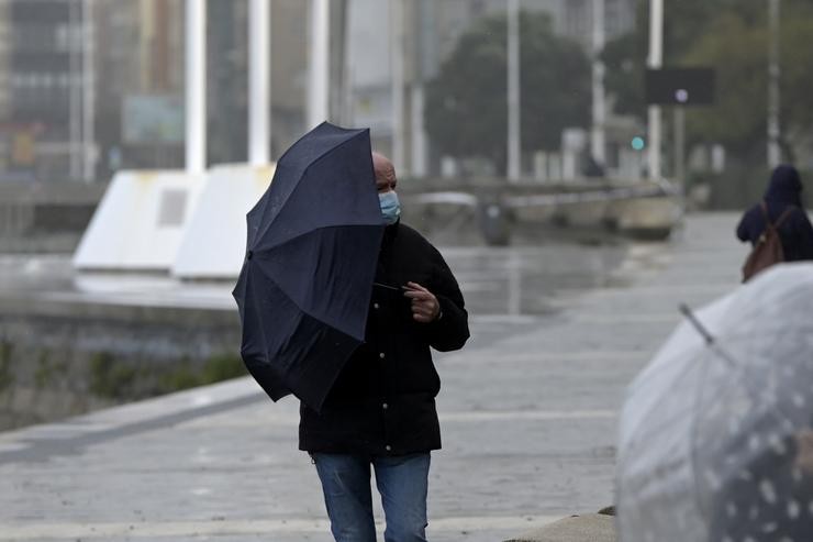 Un home cun paraugas camiña polo paseo marítimo da Coruña cun paraugas para protexerse da chuvia en pleno temporal e borrasca 