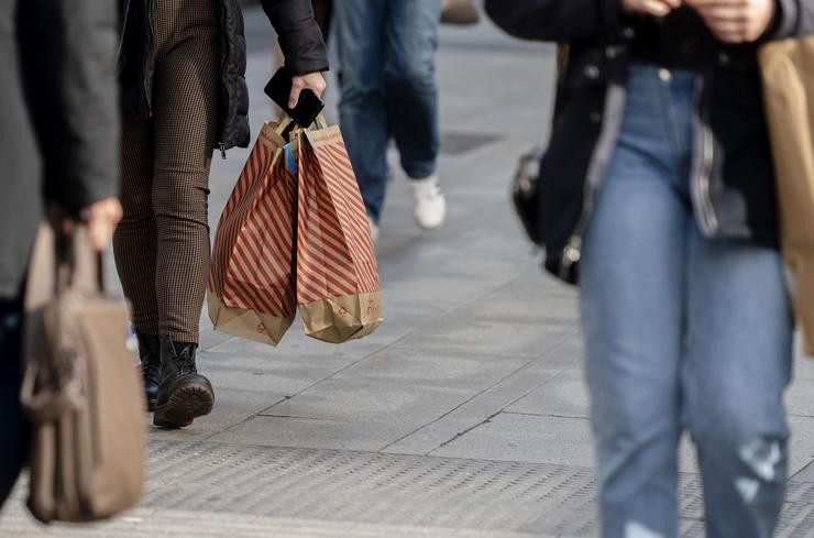 Unha muller camiña con bolsas con compras no Black Friday 