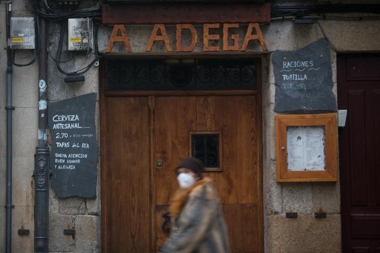 Unha muller con máscara pasa por diante dun restaurante o primeiro día do peche perimetral decretado en Lugo 