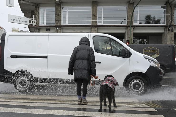 Unha muller espera co seu can antes de cruzar por un paso de peóns da Coruña, Galicia (España). M. Dylan - Europa Press 