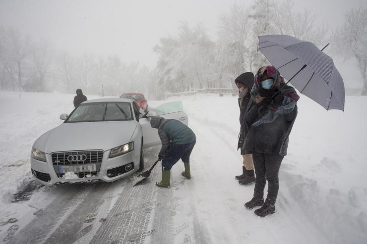 Varias persoas limpan a estrada cunha pa para axudar a un coche atrapado na neve en Pedrafita do Cebreiro. Carlos Castro - Europa Press