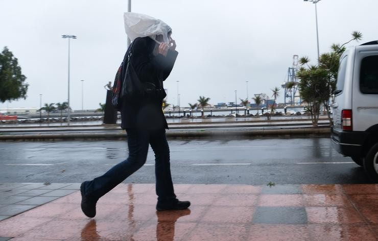 Unha persoa camiña cunha bolsa na cabeza polas fortes choivas. Europa Press
