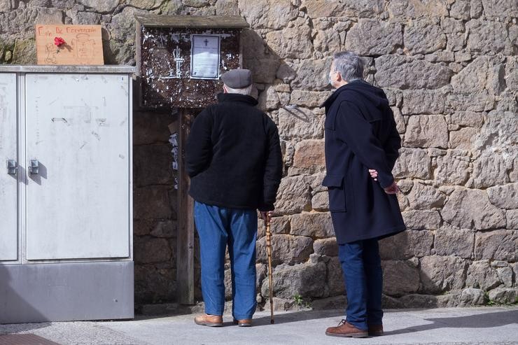 Dous homes len unha necrolóxica nunha rúa do municipio galego de Guitiriz, en Lugo / Carlos Castro - Europa Press.