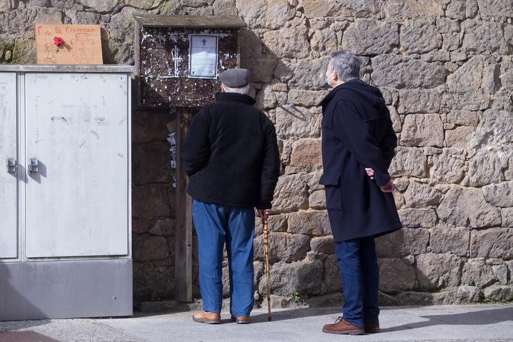 Dous homes len unha necrolóxica nunha rúa do municipio galego de Guitiriz, en Lugo / Carlos Castro - Europa Press. / Europa Press