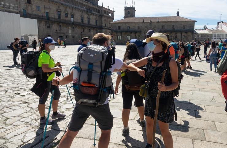 Peregrinos con máscaras saúdanse co cóbado ao chegar á  Praza do Obradoiro, no primeiro verán da pandamia Covid-19, Santiago de Compostela 26 de agosto do 2020 