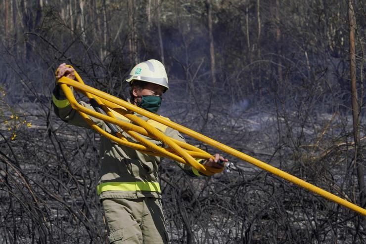 Un bombeiro apaga o incendio forestal na parroquia de Figueriras en Santiago de Compostela, A Coruña, Galicia (España), a 20 de marzo de 2021. O incendio, xa estabilizado, orixinouse ao redor das 6 da madrugada e este mediodía xa afectaba a un s. Álvaro Ballesteros - Europa Press / Europa Press