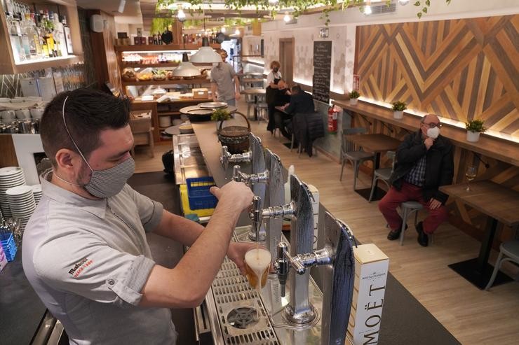 Un camareiro enche un vaso de cervexa nun restaurante durante o primeiro día da apertura parcial da hostalaría en Santiago de Compostela, a 26 de febreiro de 2021 