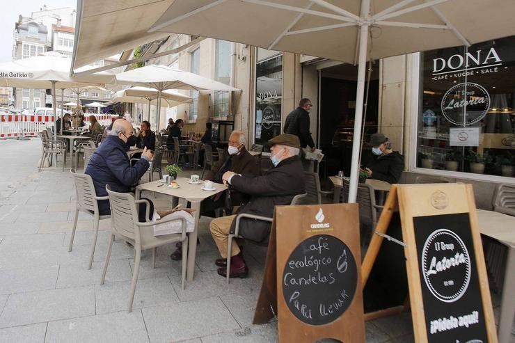 Varias persoas nunha terraza, o día en que entran en vigor novas medidas na hostalaría, en Vigo 