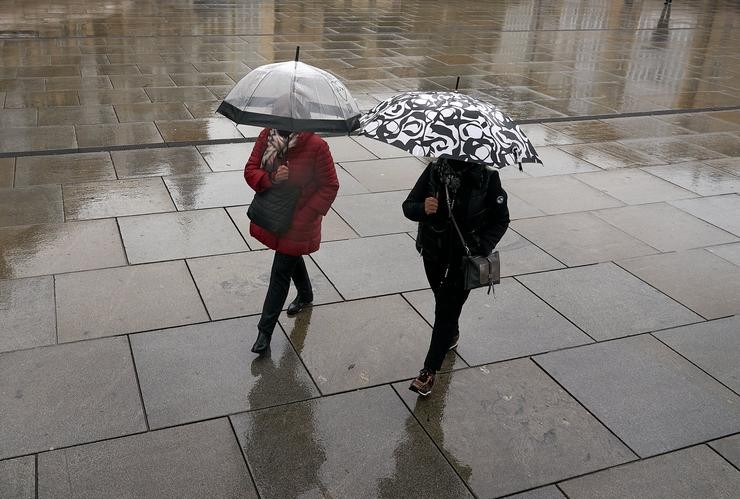 Arquivo - Dúas persoas refúxianse cun paraugas da choiva en Vitoria, País Vasco (España), a 19 de marzo de 2021. Para a xornada de hoxe, está activado o aviso amarelo por baixo dos 1.000 metros e haberá precipitacións débiles moderadas. As t. Pablo González - Europa Press - Arquivo