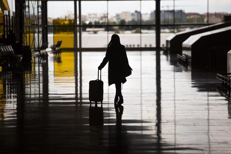 Unha pasaxeira cunha maleta chegando á terminal do aeroporto 