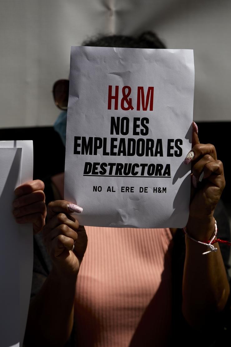 Unha persoa sostén un folio onde se pode ler "H&M non é empregadora, é destructura" durante unha concentración. Jesús Hellín - Europa Press