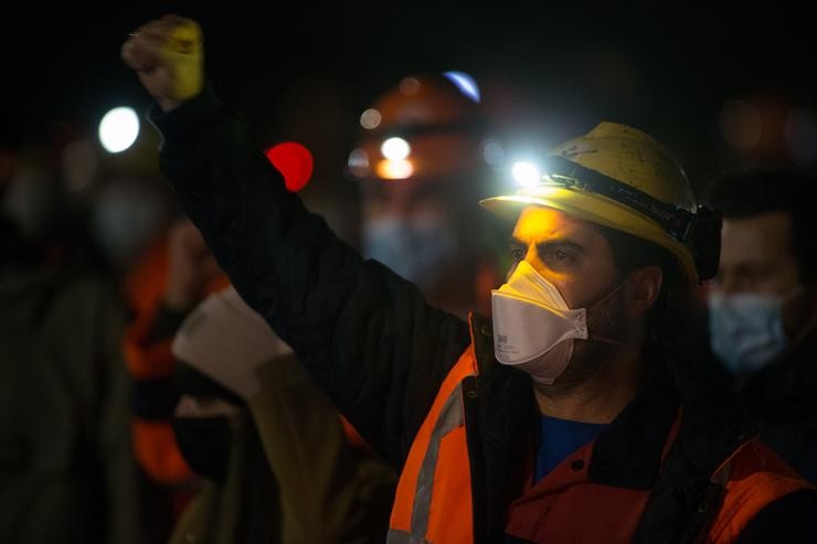 Un traballador levanta o brazo como signo de protesta durante un velorio nocturno simbólico convocado pola fábrica de Alcoa, en  San Cibrao, Cervo 