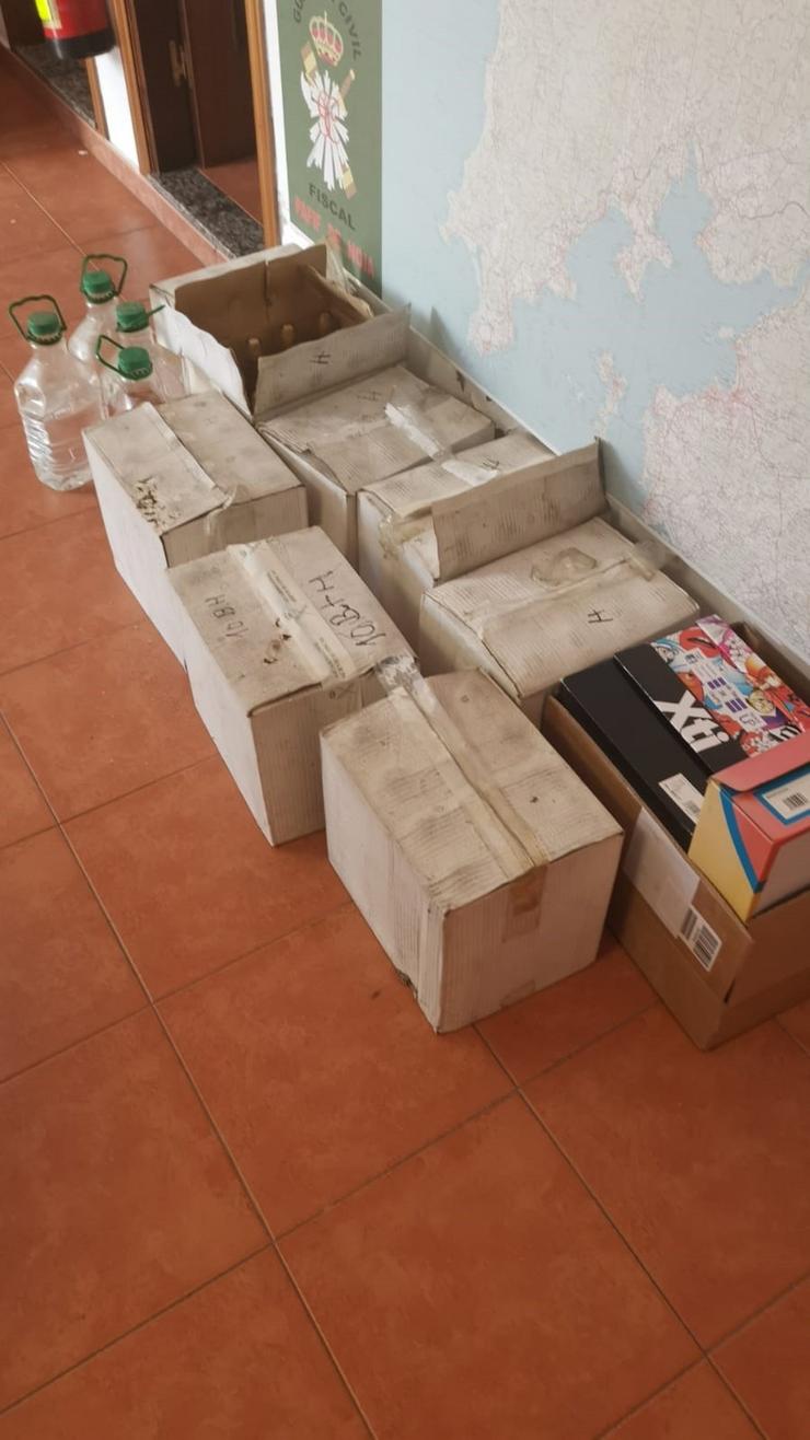 Caixas con botellas e garrafas de augardente e 60 paquetes de tabaco sen precintos fiscais intervidas nun almacén en Noia / Garda Civil.