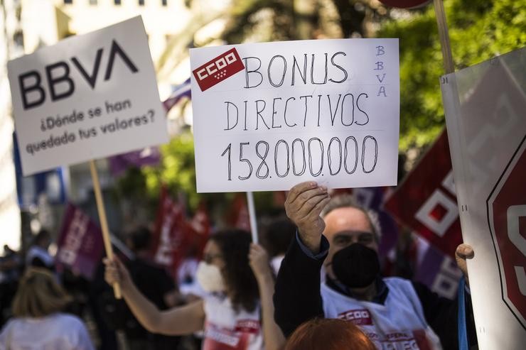 Un home suxeita un cartel no que se le: 'Bonus directivos 158.000.000' durante unha concentración contra o ERE de BBVA, no Paseo de Recoletos, a 17 de maio, en Madrid (España) 