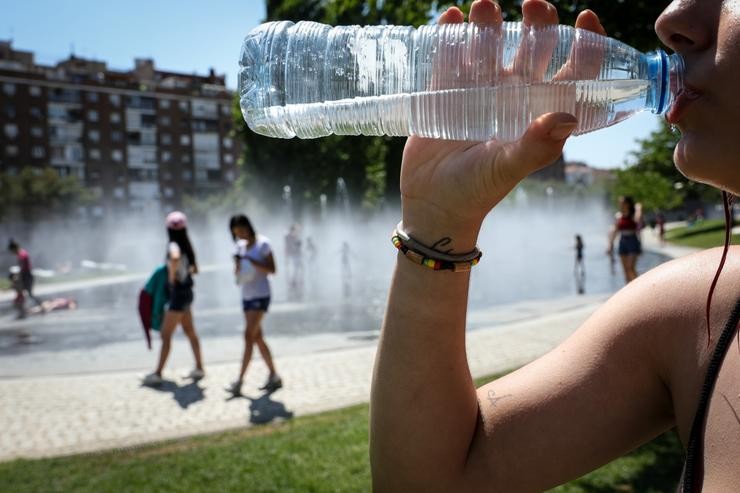 Unha muller bebe auga de botella para refrescarse na primeira onda de calor do verán de 2019 