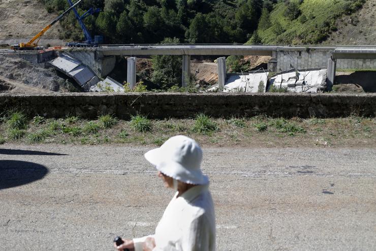 Unha muller camiña pola estrada mentres se realiza o desmonte das pilas 1 e 2 do viaduto de Ou Castro, no quilómetro 430 sentido A Coruña da autovía A-6.. Carlos Castro - Europa Press 