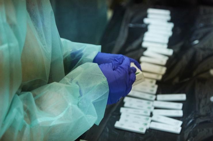 Unha enfermeira abre un test de antíxeno para realizarlle a proba a un paciente 