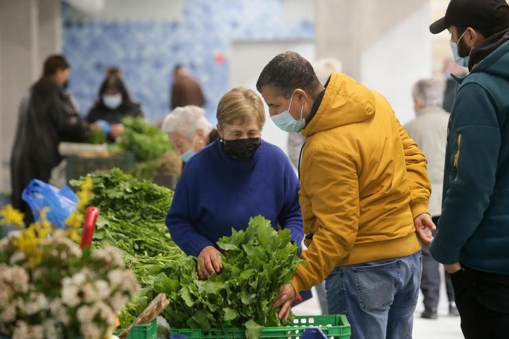 Un home compra verduras a unha vendedora local de verduras e produtos do campo, no mercado tradicional da Praza de Abastos de Lugo / Carlos Castro