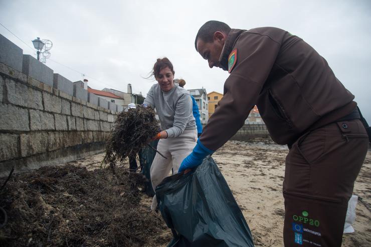 Unha voluntaria e un axente rural da zona recollen os restos de chapapote mesturados con algas, a 13 de decembro 