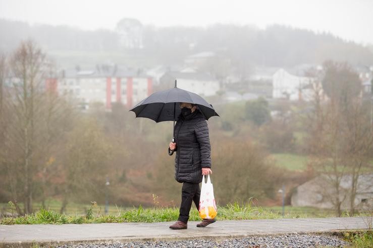 Arquivo - Unha muller pasea xunto ao Rego dá Serra cun paraugas en Paraleda, Lugo, Galicia (España), a 19 de marzo de 2021. Este municipio xunto a Maside e Vilardevós da provincia de Ourense, están pechados perimetralmente por atoparse no nivel. Carlos Castro - Europa Press - Arquivo 